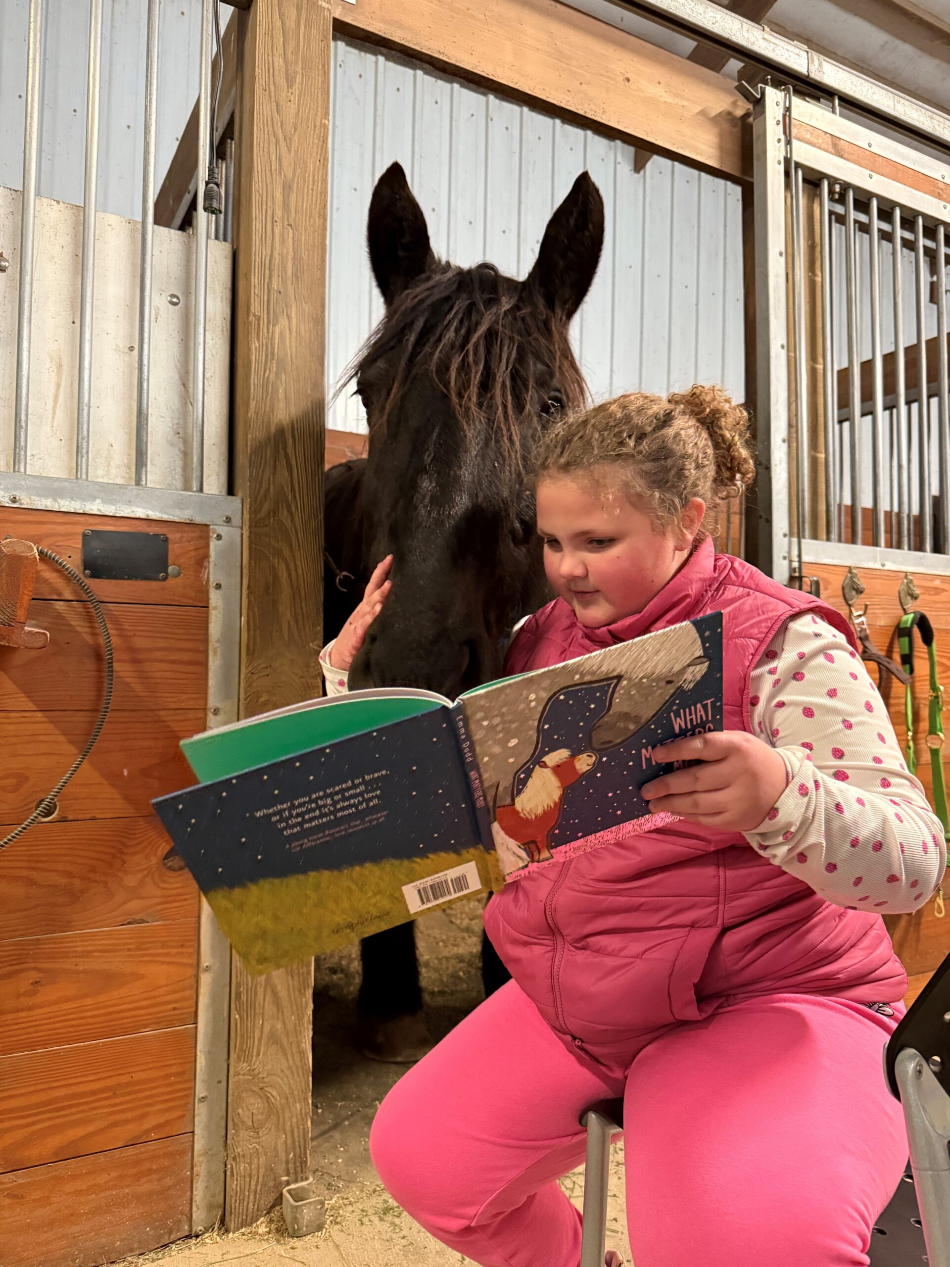 girl reading book to horse